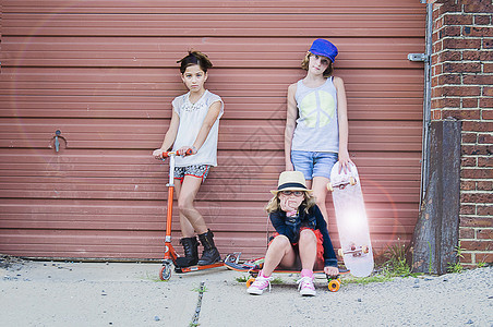 三个滑板女孩站在车库旁图片