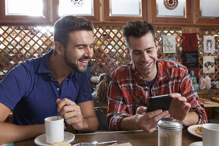 两位男性在餐厅酒吧看智能手机图片