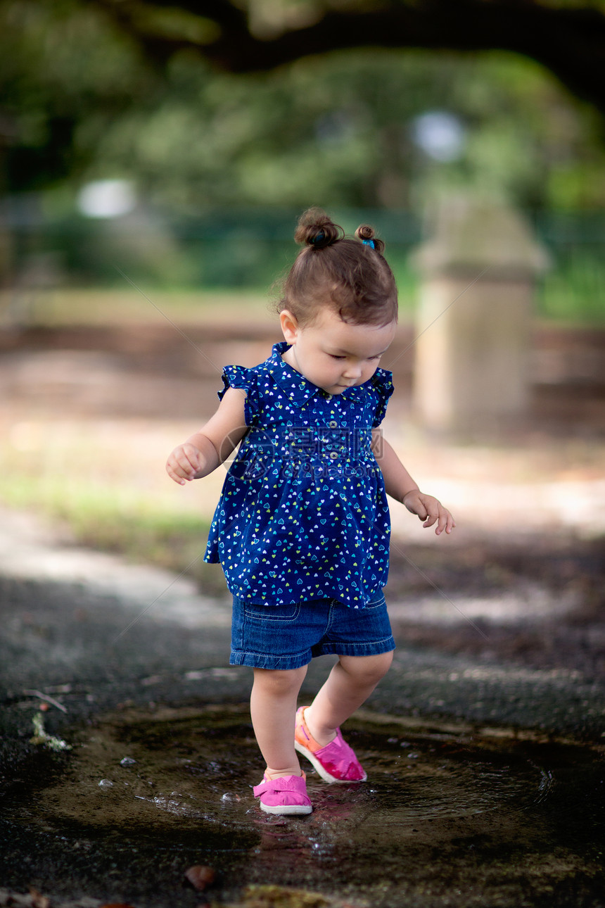 小女孩在公园踩水坑图片