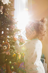 小女孩把圣诞装饰挂在树上图片