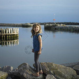 女孩站在湖边岩石上图片