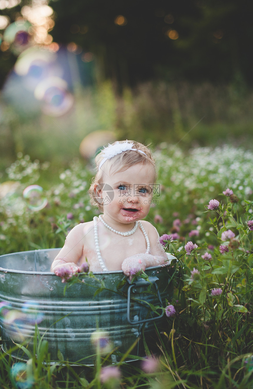女婴在野花草地的锡浴缸里洗澡图片