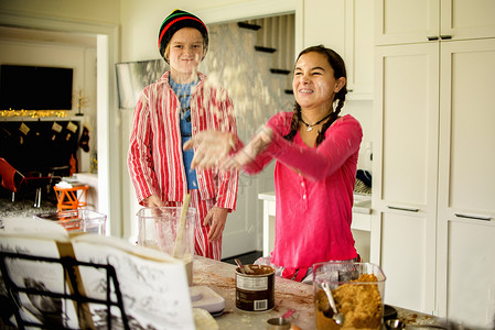 少女和兄弟在厨房里扔面粉图片