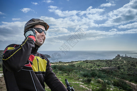 意大利撒丁岛沿海道路上的男骑行者在打电话图片