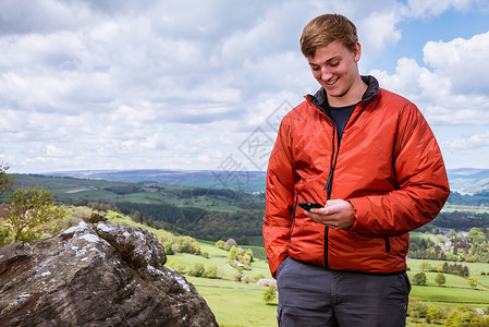 在草原上看手机的男性高清图片