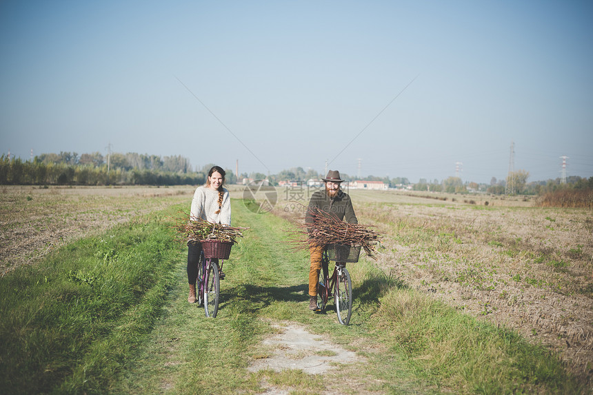 在农村道路骑自行车的年轻夫妇图片