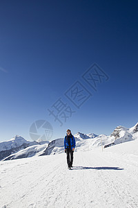 在雪覆盖的山丘中徒步旅行的运动者图片