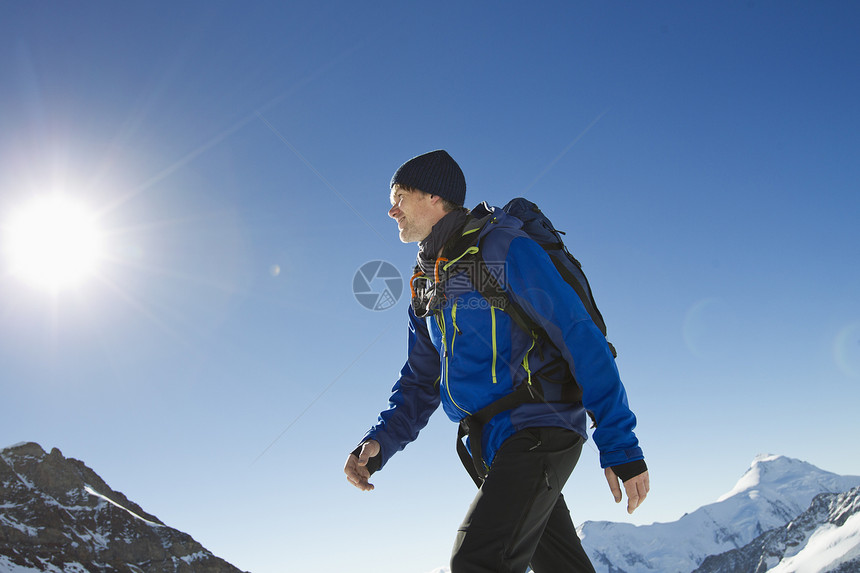 在雪覆盖的山丘中徒步的成年男子图片