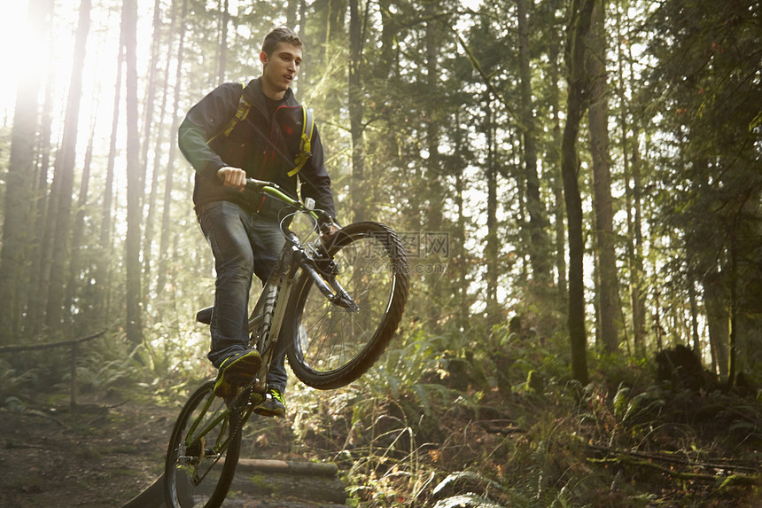 年轻人骑着山地自行车在森林里做特技图片