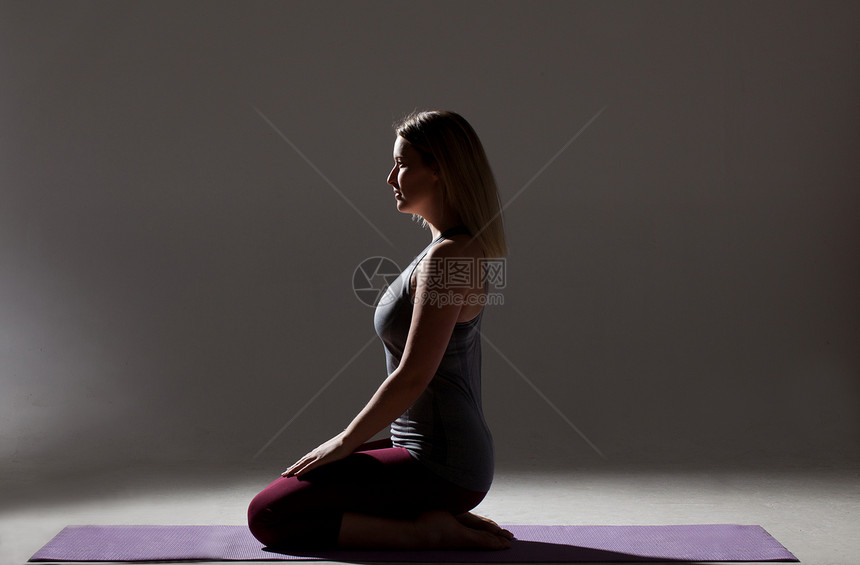 女青年跪在瑜伽垫上练瑜伽图片