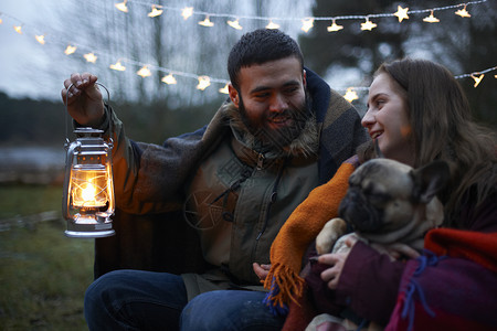 异性灯笼抱着小狗的年轻露营夫妇背景