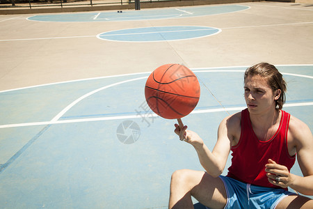 年轻男子在篮球场上转球图片