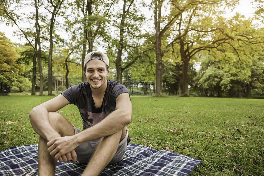 坐在公园野餐毯子上的年轻人肖像图片