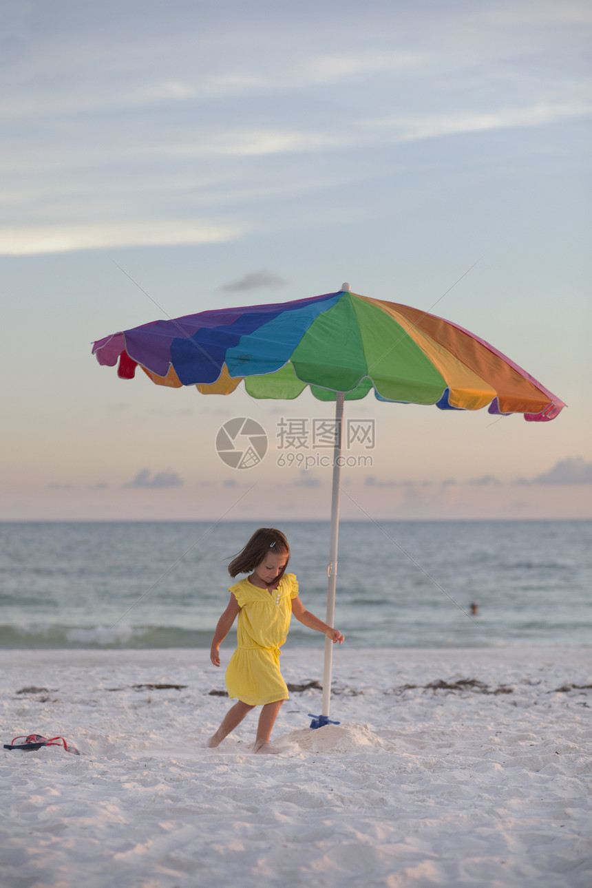 海滩上女孩在五颜六色的沙滩伞旁奔跑图片