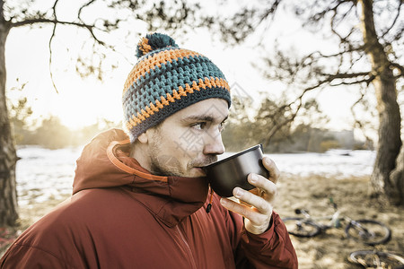 在湖边森林喝咖啡的年轻男子图片