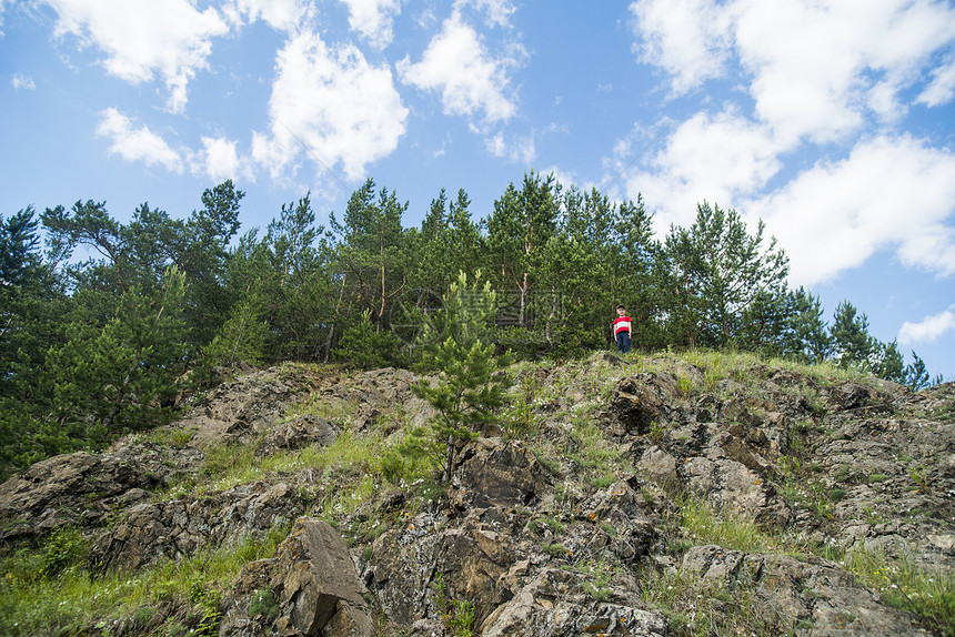 男孩站在岩石悬崖顶上图片