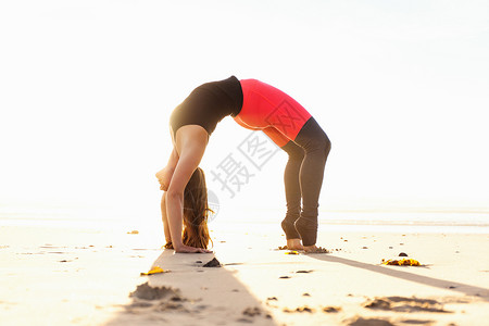 拱背在沙滩上做瑜扮演的女人背景