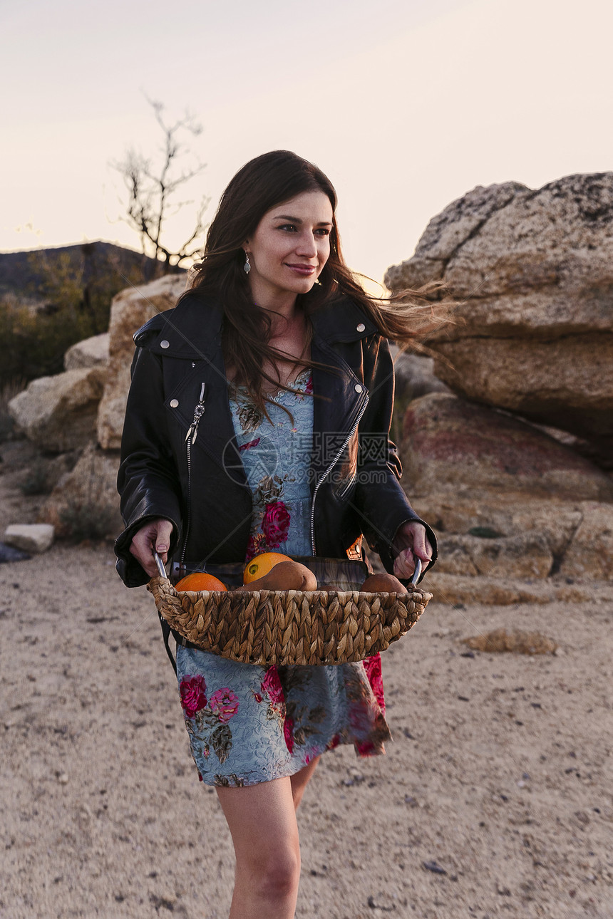 年轻妇女携带一篮水果到美国加利福尼亚州洛杉矶的沙漠野餐图片