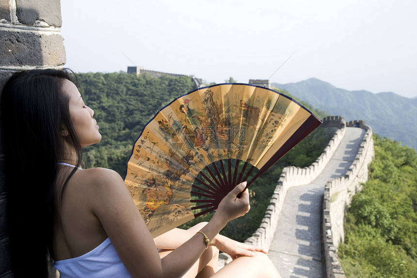 北京长城上手持扇子的中年女游客的后视图图片