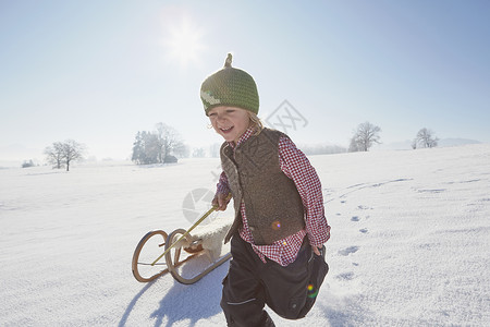 年轻男孩跑拉着雪橇图片