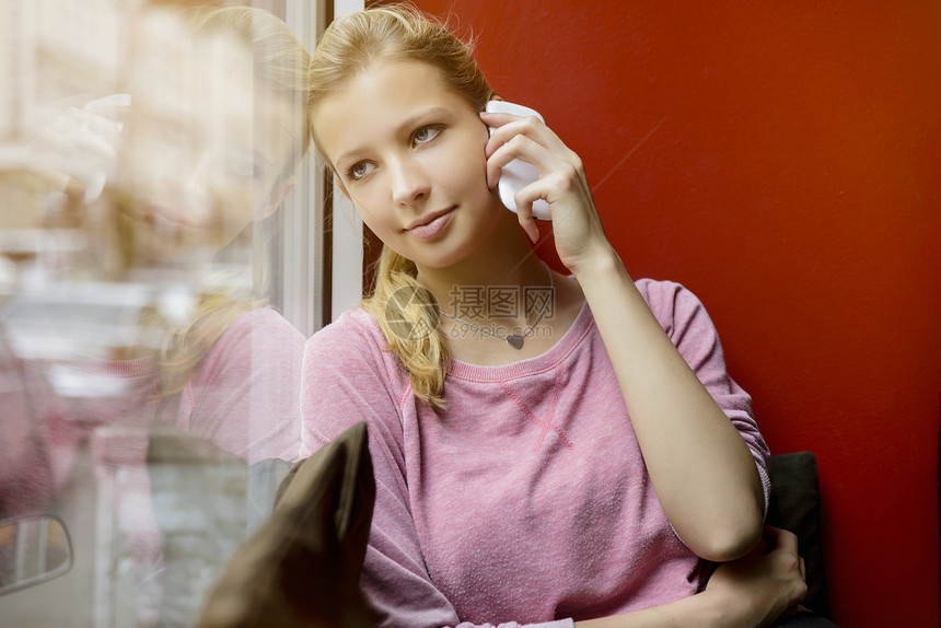 年轻女子从咖啡厅窗外观视同时在智能手机上聊天图片