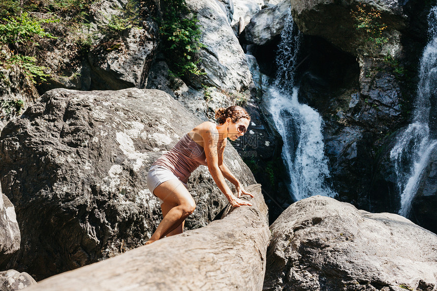 一个女人爬在瀑布附近的岩石上图片