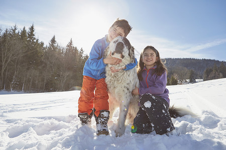 享受在雪中玩耍的儿童和狗狗高清图片