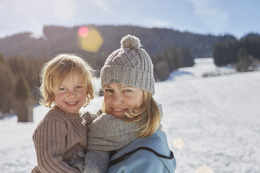 母亲和儿子在雪中享受阳光图片
