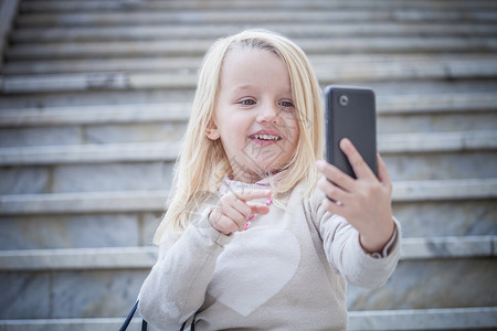 楼梯上的年轻女孩正在使用智能手机自拍图片