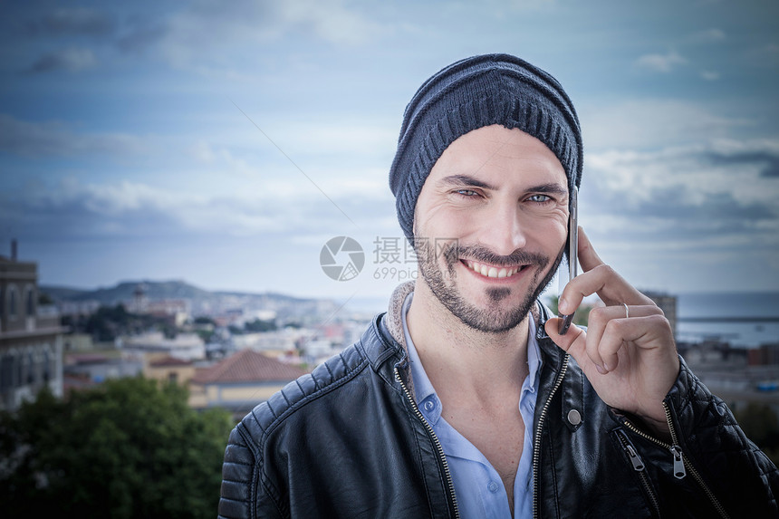 男青年在屋顶上用智能手机打电话图片