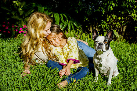 坐在花园草地上的母女和狗图片