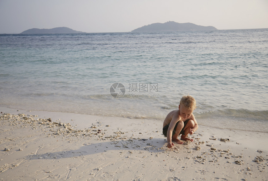 马来西亚拉瓦岛沙滩上玩沙子的男孩图片