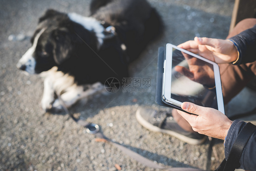 男子用平板给宠物狗拍照图片