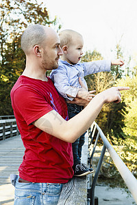 男子抱着孩子站在桥上看风景图片