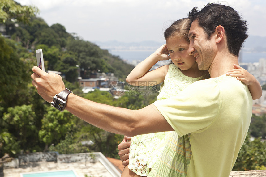 父亲抱着女儿用手机自拍图片