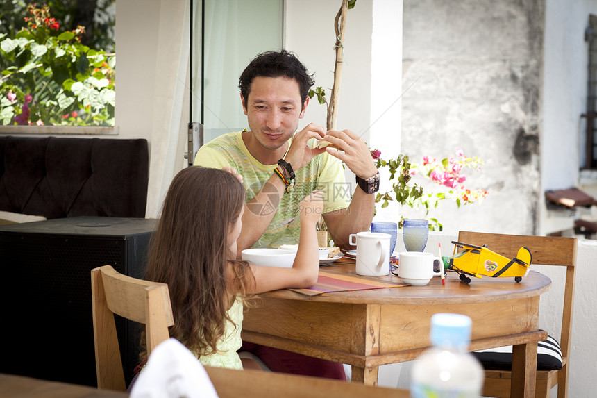 父亲和女儿一起坐在早餐桌上图片