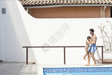父亲和女儿在户外游泳池旁玩耍图片