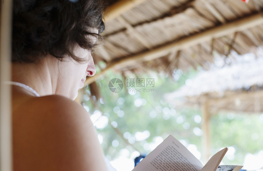 在泰国克拉丹海滩小屋外看书的妇女图片