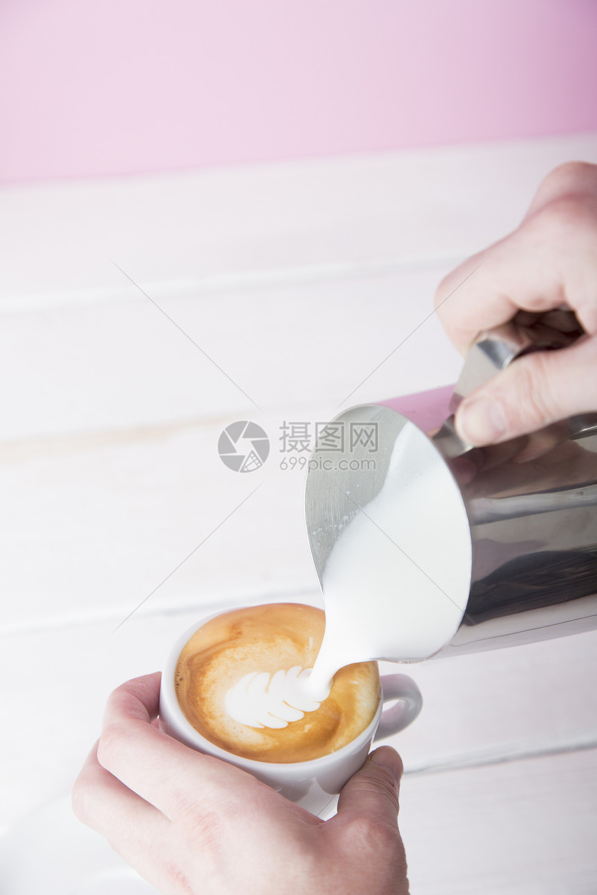 人手往咖啡杯里倒冷冻的牛奶图片