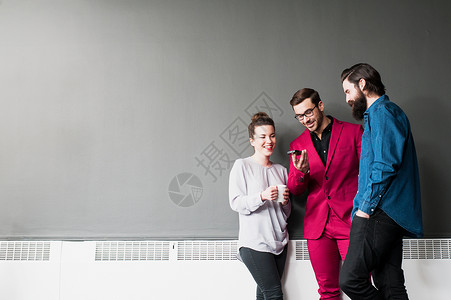 三个人站在墙边看手机图片