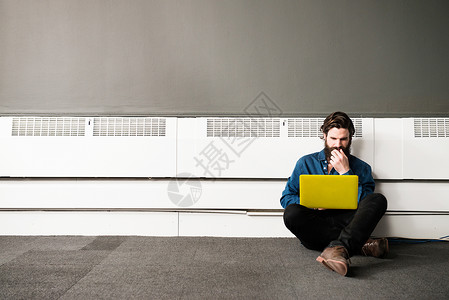 男人用笔记本电脑坐在办公室楼层图片