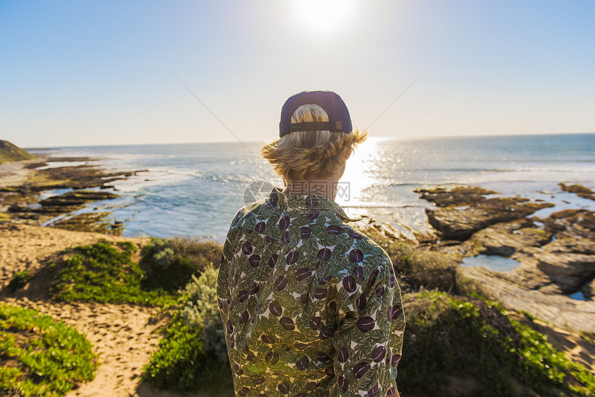 年轻人背对着站立看着海洋图片