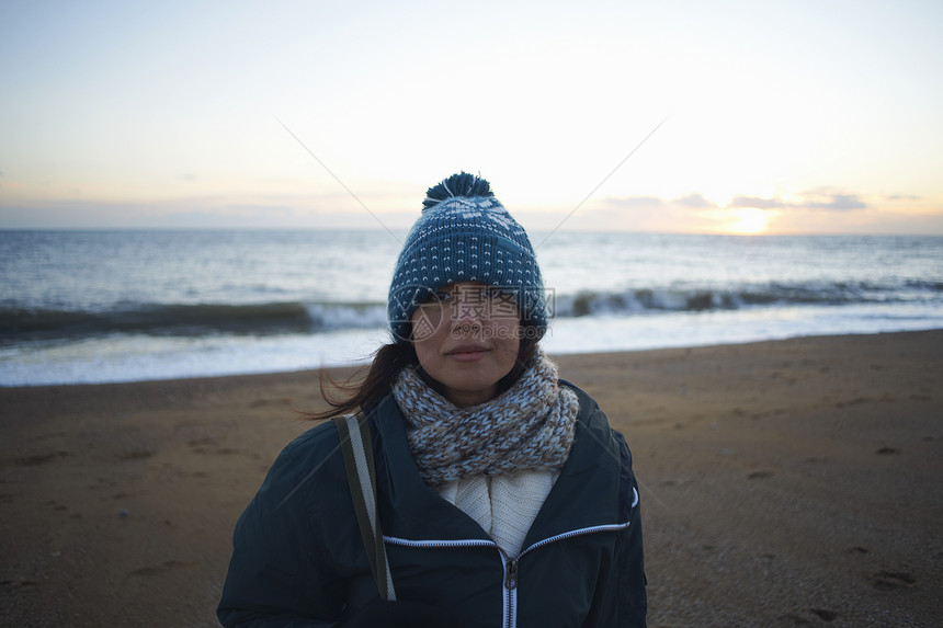 黄昏海滩上戴着帽子的成年女子肖像图片