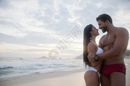 情侣在沙滩上拥抱着对视微笑背景图片