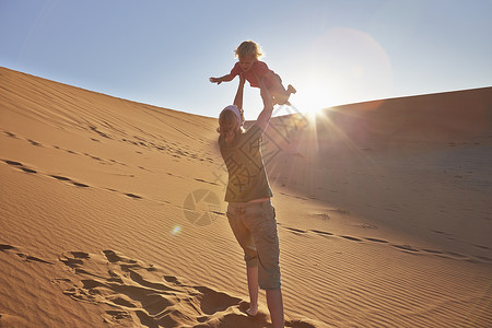 索索母亲与儿子在沙丘上玩耍背景