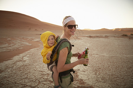 在沙丘上行走背着孩子的母亲图片