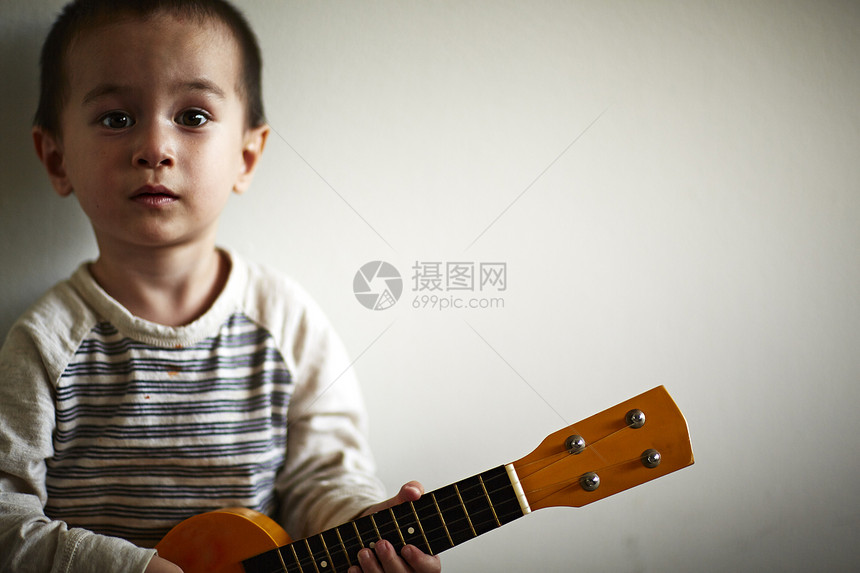 男孩抱着吉他靠在墙壁上图片