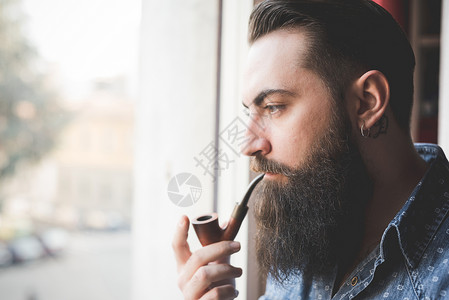 长胡子的年轻人窗边抽烟图片