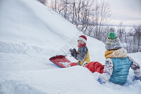 两兄弟在雪覆盖的山上玩耍图片