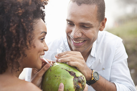 海滩分享椰子汁的夫妇图片